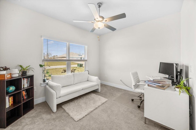 carpeted office space featuring a ceiling fan and baseboards