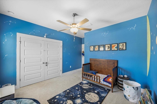 carpeted bedroom featuring a textured ceiling, a ceiling fan, and a closet