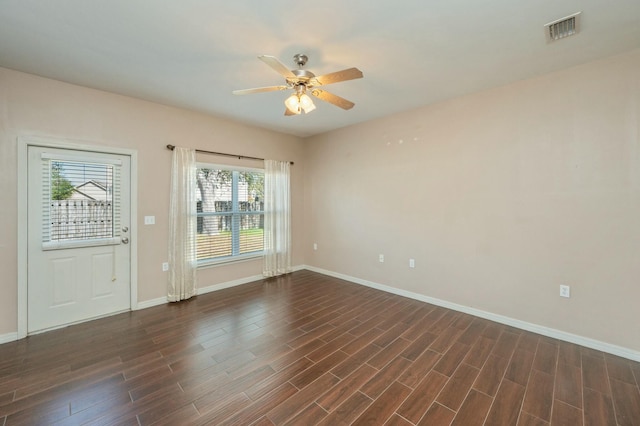 empty room featuring a ceiling fan, baseboards, visible vents, and dark wood-type flooring