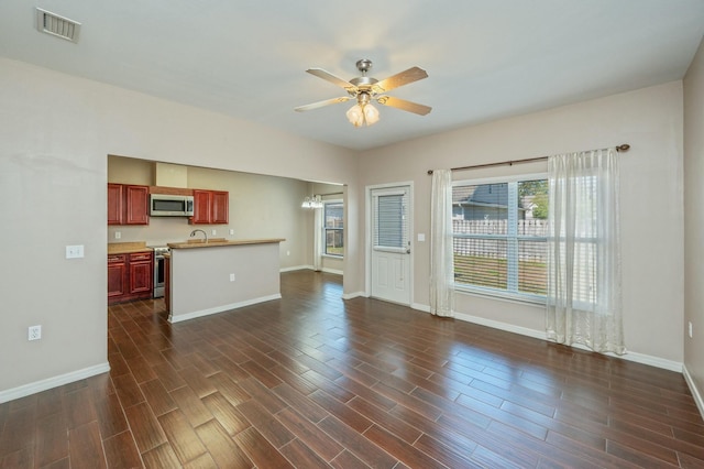 unfurnished living room with baseboards, visible vents, dark wood finished floors, and ceiling fan with notable chandelier