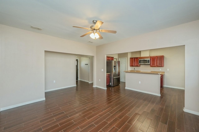 unfurnished living room with dark wood-style floors, a ceiling fan, and baseboards