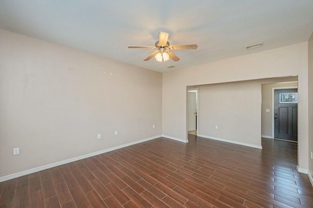 spare room with dark wood-style floors, a ceiling fan, visible vents, and baseboards