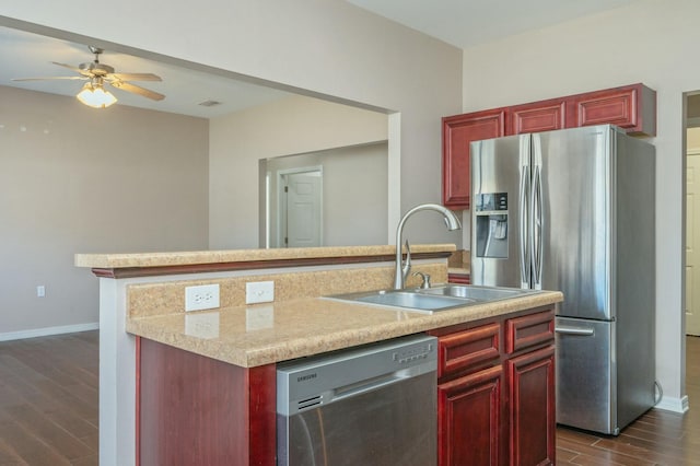 kitchen featuring dark wood-type flooring, stainless steel appliances, dark brown cabinets, light countertops, and a sink