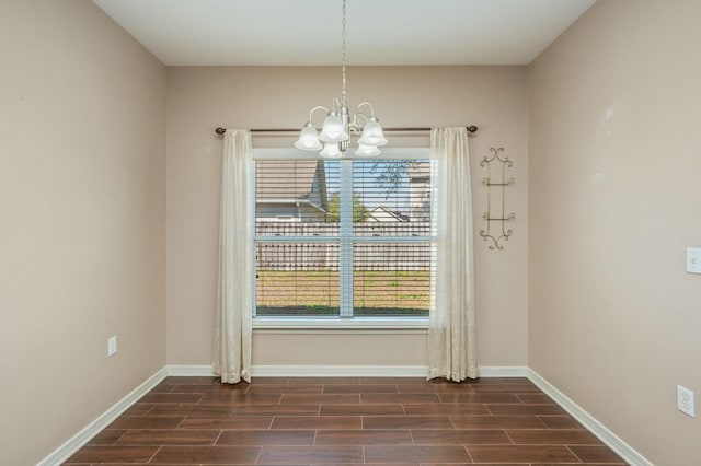 unfurnished dining area featuring wood tiled floor, baseboards, and a notable chandelier