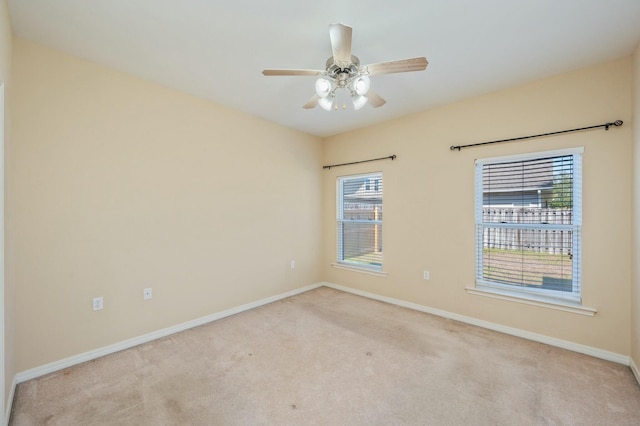 carpeted spare room featuring ceiling fan and baseboards