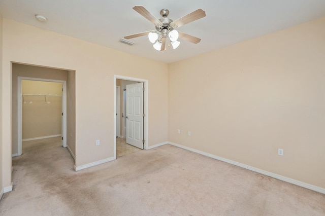 unfurnished bedroom with light colored carpet, visible vents, baseboards, a closet, and a walk in closet