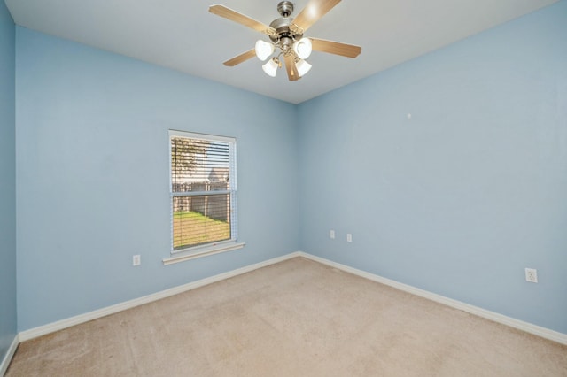 carpeted empty room with a ceiling fan and baseboards