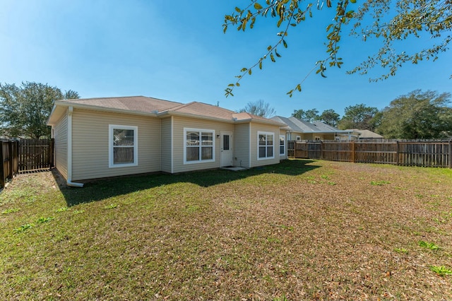 back of property with a fenced backyard and a lawn