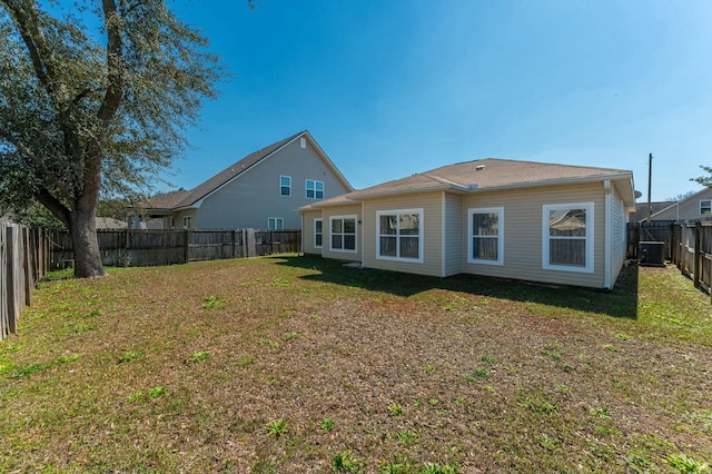 rear view of house featuring a fenced backyard, central AC, and a lawn