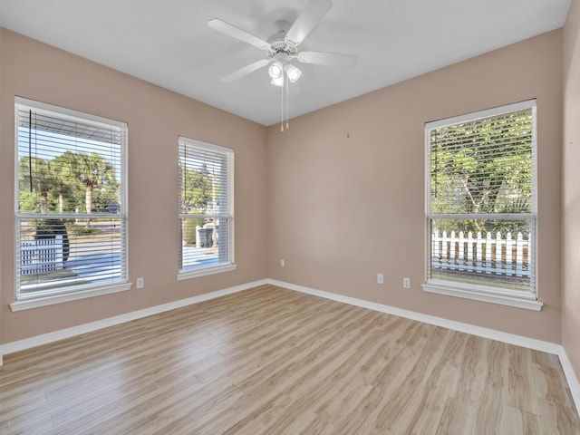 spare room featuring light wood-type flooring, baseboards, and a ceiling fan