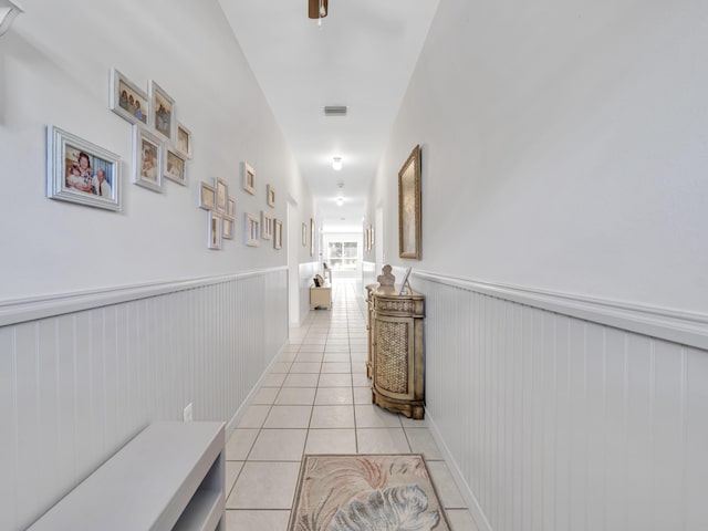 hallway featuring wainscoting and light tile patterned flooring