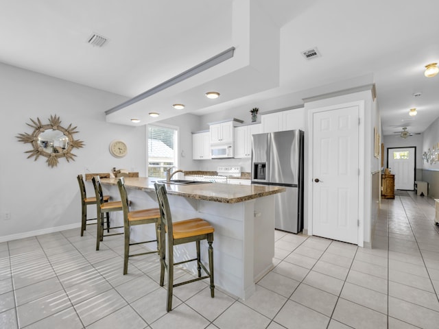 kitchen with stainless steel fridge, visible vents, white microwave, a kitchen breakfast bar, and a peninsula