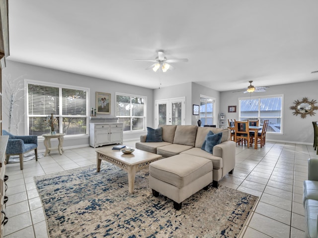 living room featuring light tile patterned floors, ceiling fan, french doors, and baseboards