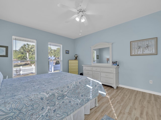 bedroom featuring a ceiling fan, light wood-style flooring, and baseboards