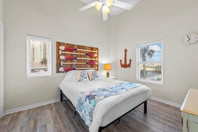 bedroom featuring multiple windows, baseboards, and wood finished floors