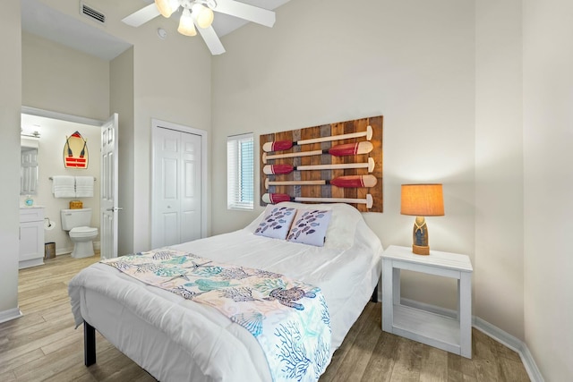 bedroom featuring baseboards, visible vents, wood finished floors, high vaulted ceiling, and a closet