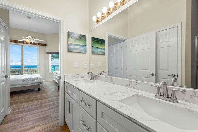 bathroom featuring double vanity, wood finished floors, a sink, and ensuite bathroom