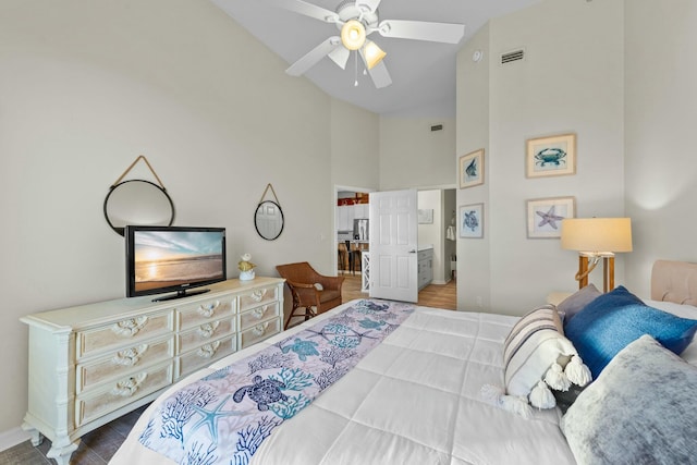 bedroom with high vaulted ceiling, wood finished floors, visible vents, a ceiling fan, and stainless steel refrigerator with ice dispenser