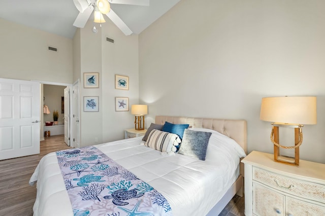 bedroom with visible vents, connected bathroom, ceiling fan, wood finished floors, and high vaulted ceiling