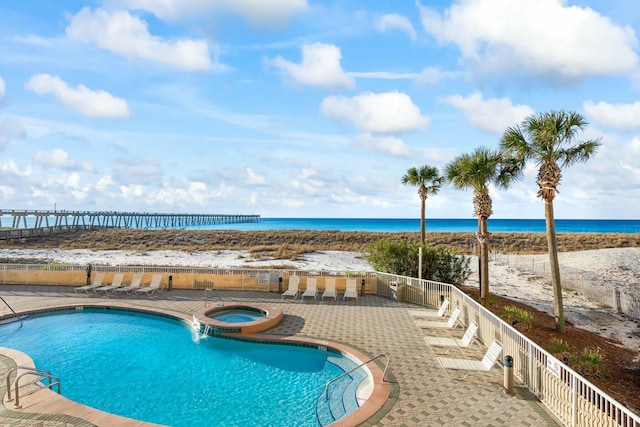 view of swimming pool with a patio area, a water view, and a hot tub