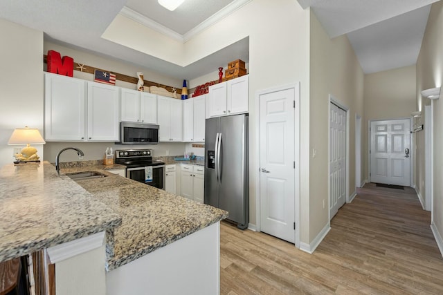 kitchen with a sink, white cabinetry, appliances with stainless steel finishes, light stone countertops, and light wood finished floors