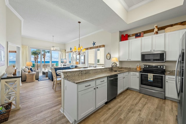 kitchen featuring stainless steel appliances, a peninsula, a sink, light wood-style floors, and ornamental molding