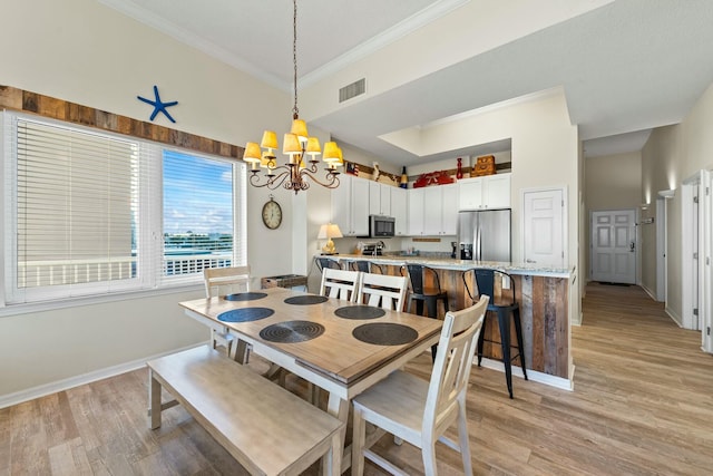 dining area with a chandelier, ornamental molding, visible vents, and light wood-style floors