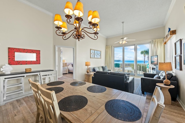 dining room featuring a textured ceiling, ornamental molding, ceiling fan with notable chandelier, and wood finished floors