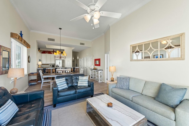 living area featuring ceiling fan with notable chandelier, wood finished floors, visible vents, and baseboards