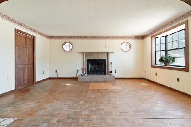 unfurnished living room with parquet flooring, a fireplace, baseboards, and a textured ceiling