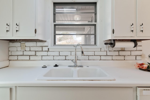 kitchen featuring a sink, white dishwasher, light countertops, and white cabinetry