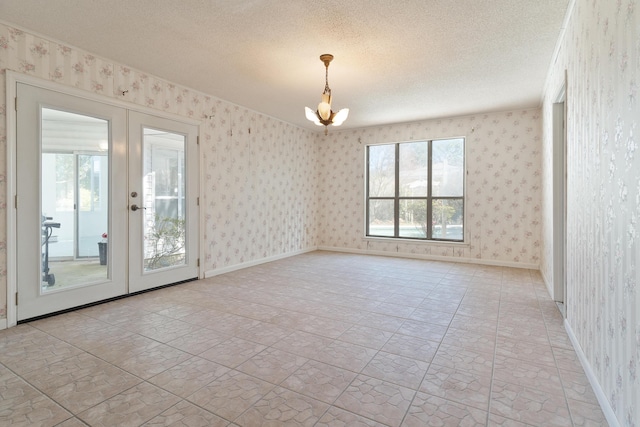 unfurnished room with wallpapered walls, baseboards, french doors, a notable chandelier, and a textured ceiling