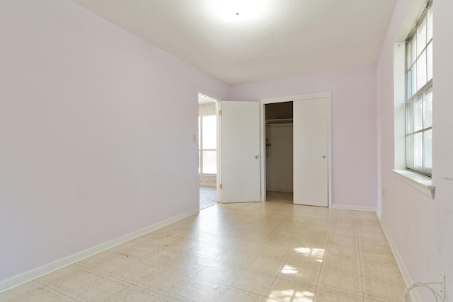 unfurnished bedroom with a closet, light floors, and baseboards