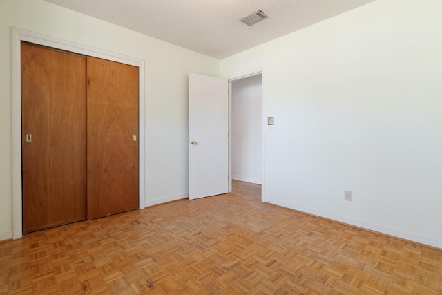 unfurnished bedroom featuring a closet, visible vents, a textured ceiling, and baseboards