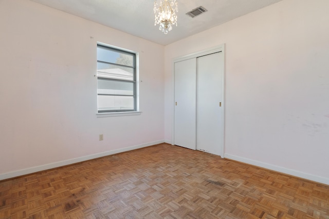 unfurnished bedroom featuring visible vents, baseboards, a closet, and a chandelier