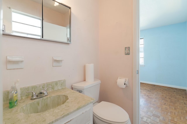 half bathroom with plenty of natural light, toilet, vanity, and baseboards