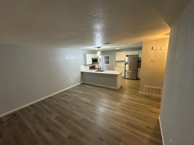 kitchen featuring stainless steel appliances, dark wood-type flooring, a peninsula, visible vents, and white cabinets