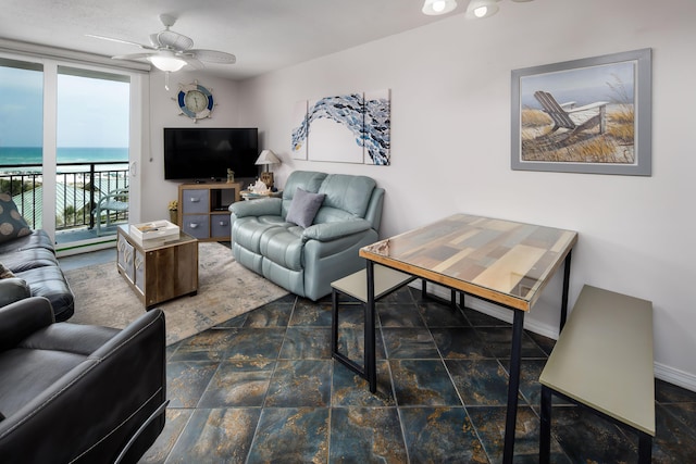 living room with a baseboard heating unit, ceiling fan, and stone finish floor