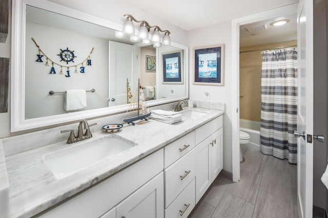 full bath with toilet, double vanity, a sink, and shower / tub combo with curtain