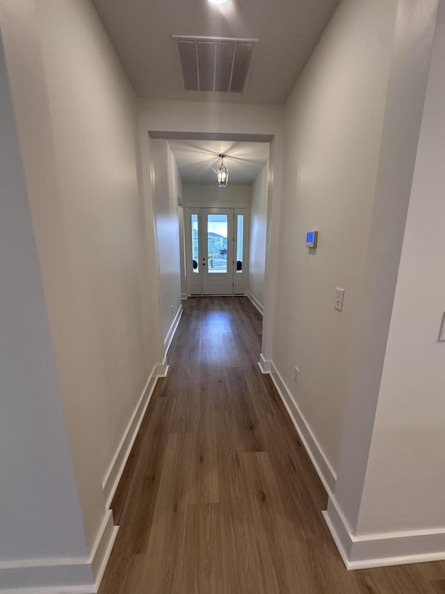 hallway featuring dark wood-style flooring, visible vents, and baseboards