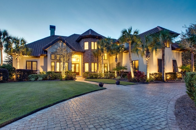 view of front of home featuring stone siding, a lawn, and stucco siding