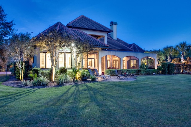 back of house with a patio area, a yard, a tiled roof, and stucco siding