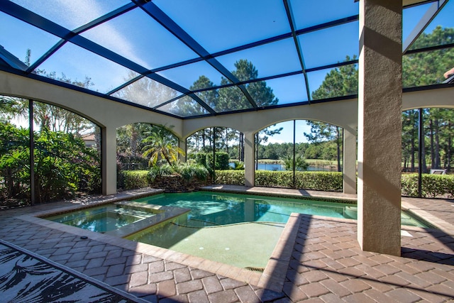 view of pool with a pool with connected hot tub, a patio area, glass enclosure, and a water view