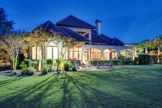 rear view of property featuring a patio area, a tiled roof, stucco siding, and a yard