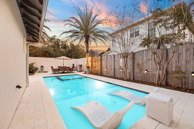 view of swimming pool featuring a diving board, a patio, outdoor dining area, and a fenced backyard