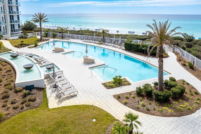 pool with a water view, a patio area, and fence