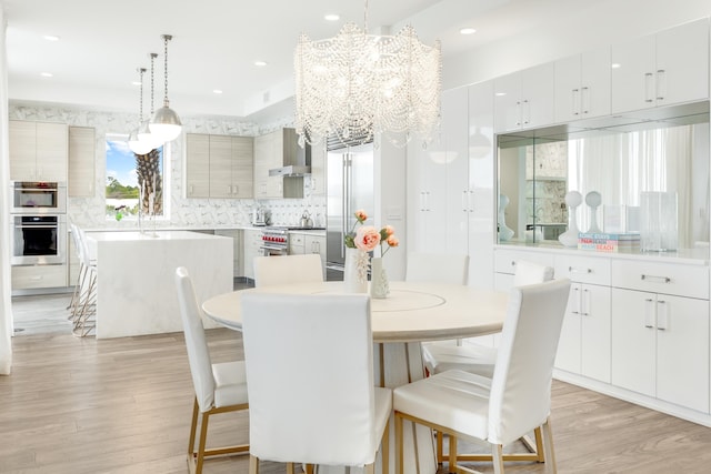 dining room with a notable chandelier, light wood-style flooring, and recessed lighting