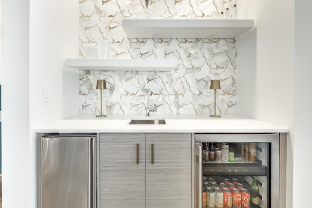 bar featuring tasteful backsplash, wine cooler, indoor wet bar, refrigerator, and a sink