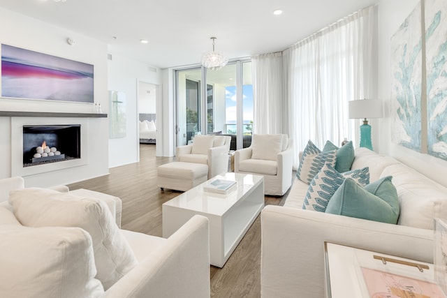 living room with an inviting chandelier, a wall of windows, wood finished floors, and recessed lighting