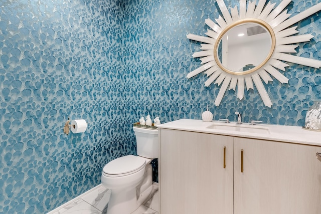 bathroom featuring marble finish floor, vanity, toilet, and wallpapered walls